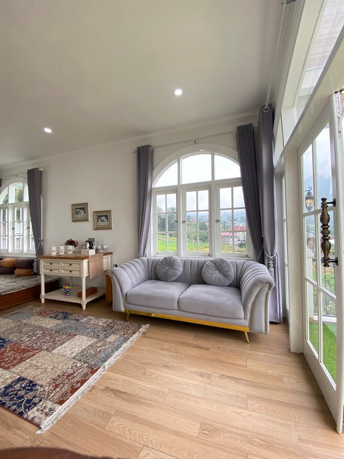 Home Spacious living room with a sofa by large windows, offering a cozy and bright atmosphere.